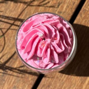 Vue de dessus de la bougie artisanale Monoï Passion, crème rose fouettée et mèche centrée