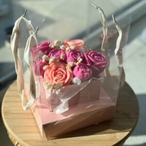 Bouquet de fondants parfumés en forme de roses, présenté dans une boîte transparente avec anses en tissu, création artisanale signée Muri Créations – fondants faits main à base de cire végétale