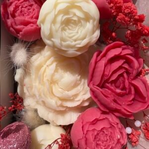 Gros plan sur les fleurs fondantes parfumées en cire végétale, couleurs rose et ivoire, détail du travail artisanal – Muri Créations